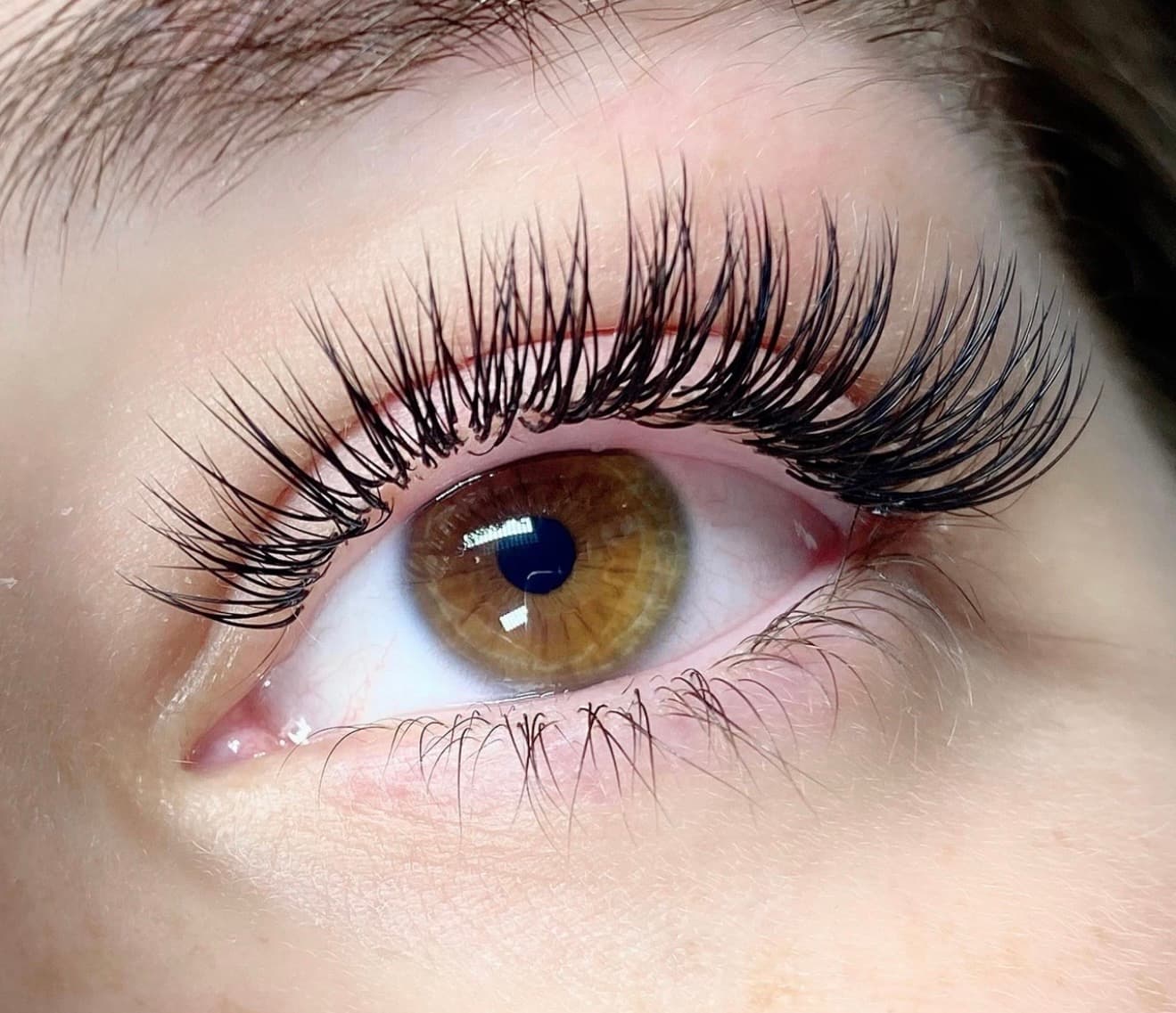 Hazel eye with long, voluminous black eyelash extensions and a dramatic upward curl.